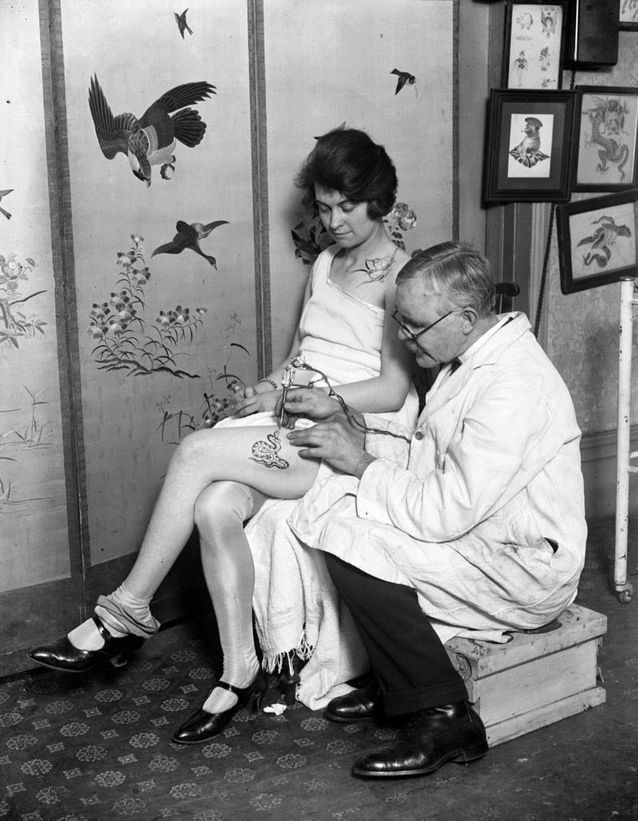 George Burchett tatouant une jeune femme.